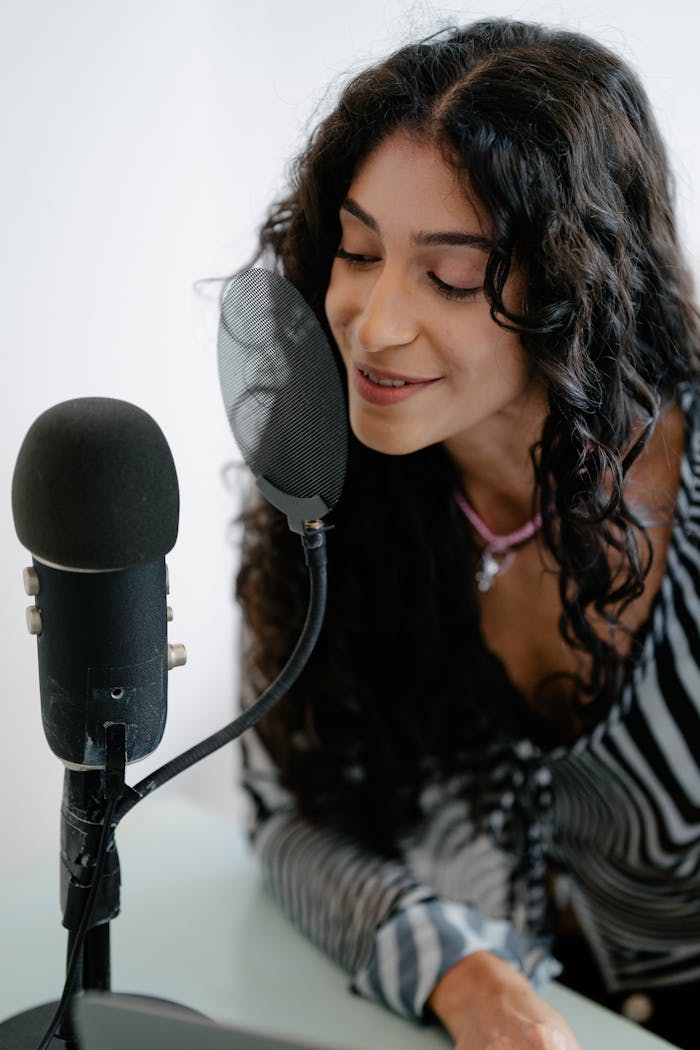 pexels-photo-13929777 Young woman recording podcast using a professional microphone indoors. Perfect for tech and lifestyle themes.