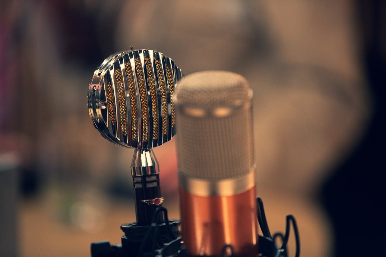 Close-up of a vintage and a modern microphone in a recording studio with a warm ambiance.